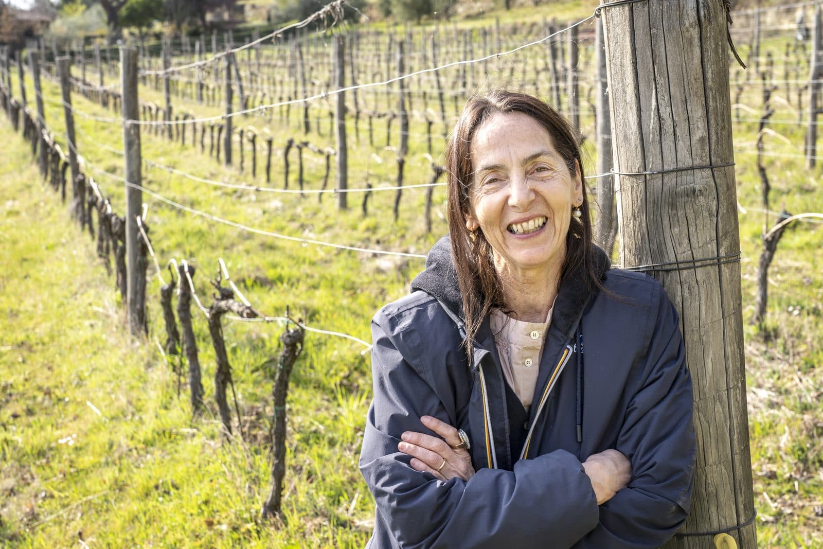 Susanna Grassi smiling, arms folded, in the vineyard at Casole